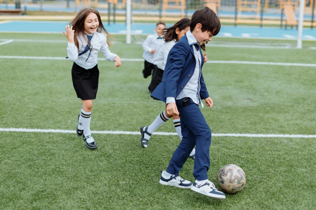 Group of children playing soccer on a school field, enjoying outdoor leisure time.